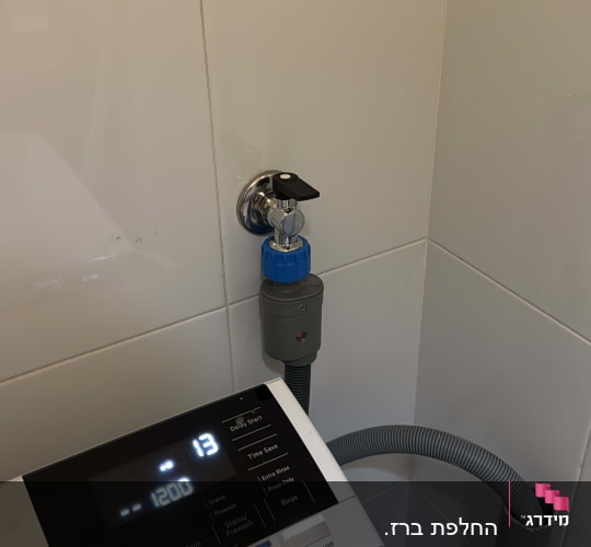 ברז מים מחובר למכונת כביסה עם צינור ניקוז